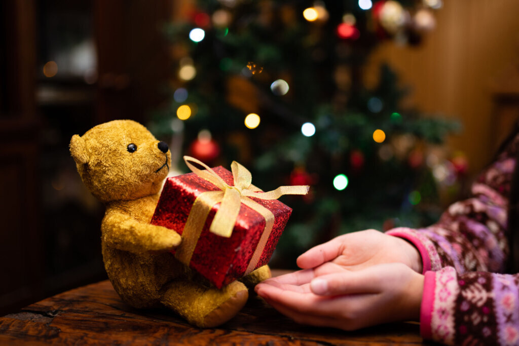Girl receiving a Christmas gift from a teddy bear