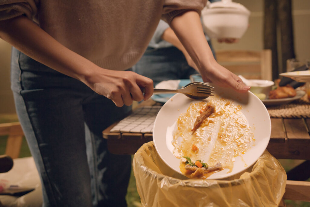 Group of people party at home after meal eating throw away leftovers food to plastic bag junk trash bin. Net zero waste go green eco friendly lifestyle reduce household scrap. Save the planet earth.
