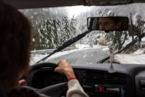 Woman Driving in Bad Winter Conditions of the Road Snowing on the road over shoulder view