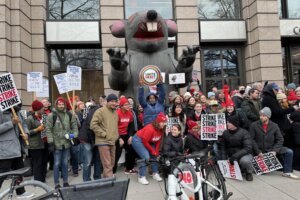 A group photo of strikers in front of an inflatable rat