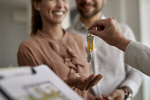 Close up of couple receiving new house keys from real estate agent.