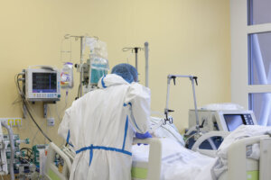 The nurse is talking with a patient who fell ill with a new type of coronavirus covid 19. Male nurse with protective coverall clothing in intensive care unit in hospital.