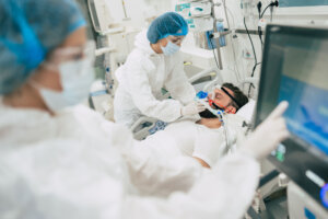 Coronavirus covid 19 infected patient in a quarantine ward at the hospital with doctors in protective suits while they making disease treatment of him
