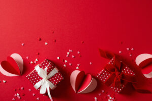 Red background flat lay with gift, paper hearts, gift box, valentines day, mothers day concept