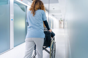 Rear view of a nurse pushing wheelchair with woman