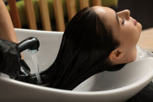 Hairdresser rinsing out dye from woman's hair in beauty salon