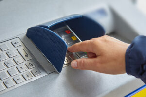 A female hand dials a personal code on the ATM keyboard openly. The concept of lack of caution, carelessness, money transfers and theft of personal information. Close up