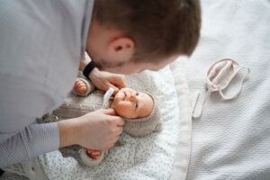 Dad changes clothes for newborn on bed. dad on maternity leave