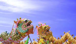 Two colorful Chinese dragon dance performances against blue sky background during Chinese New Year celebrate festival