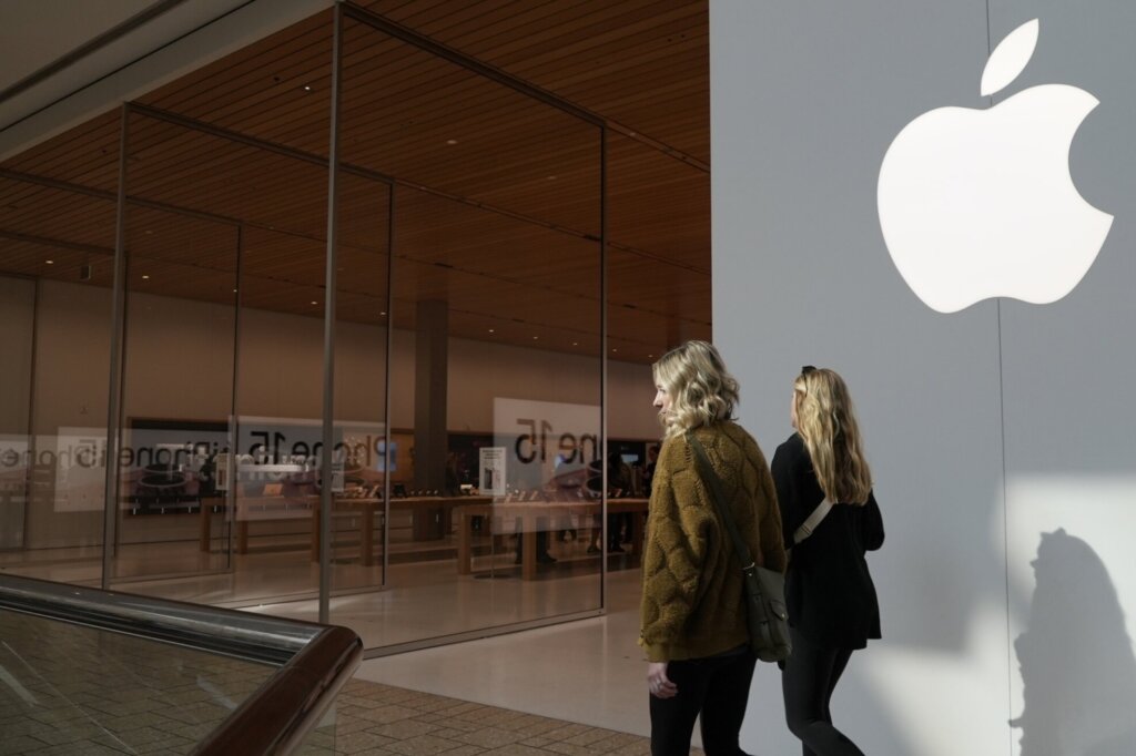 Pair of women walking past an Apple retail store