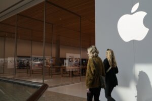 Pair of women walking past an Apple retail store