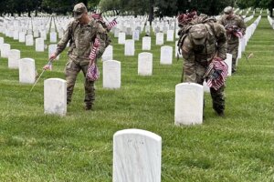 Soldiers placing flags on tombstones