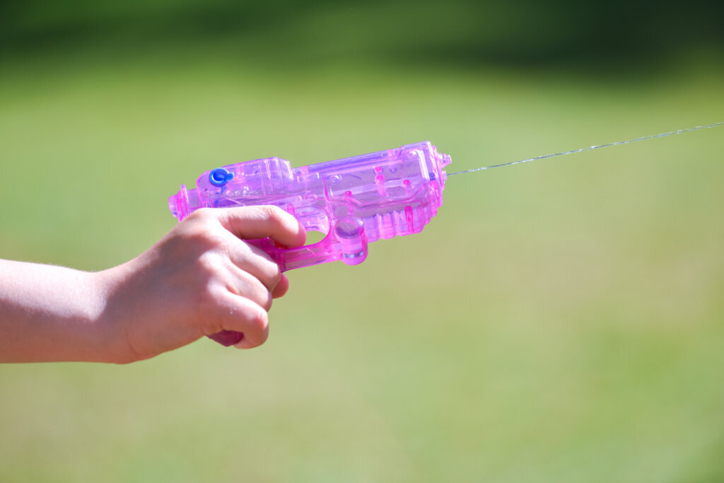 Pink water gun shooting water close up in a garden