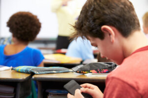 Pupil Sending Text Message On Mobile Phone In Class