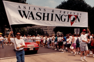 People holding banner in front of car at parade.