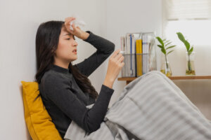 Asian female, young woman having cold, high temperature on bed