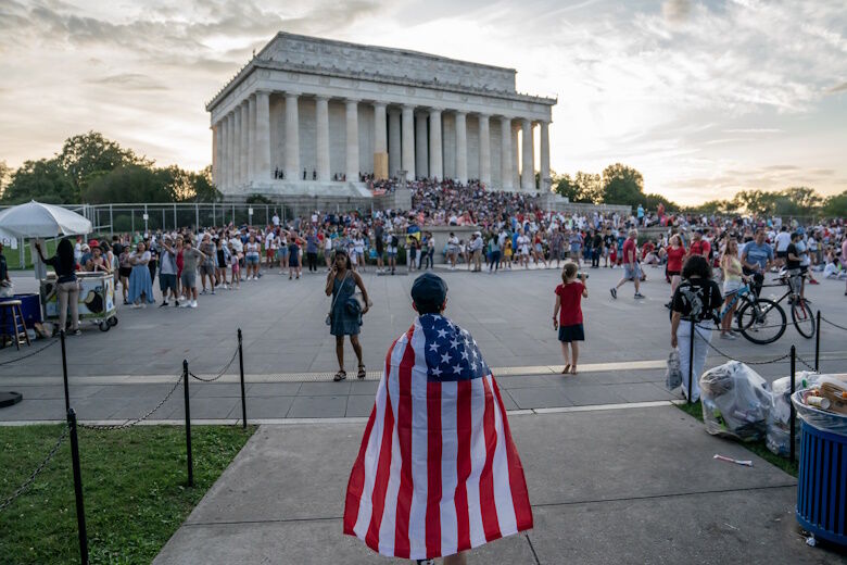 Attendee wearing an American Flag as a cape approaches the Lincoln Memorial