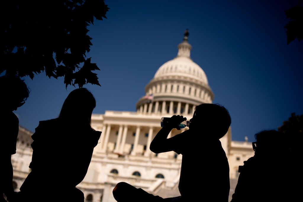 Young person drinking from water bottle in front of the U.S. Capitol