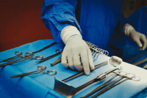 Close up of surgeons hand holding surgical instruments in the operating room, Surgical tools lying on the table