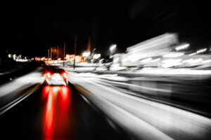 Concept photo of car speeding along a roadway at night.