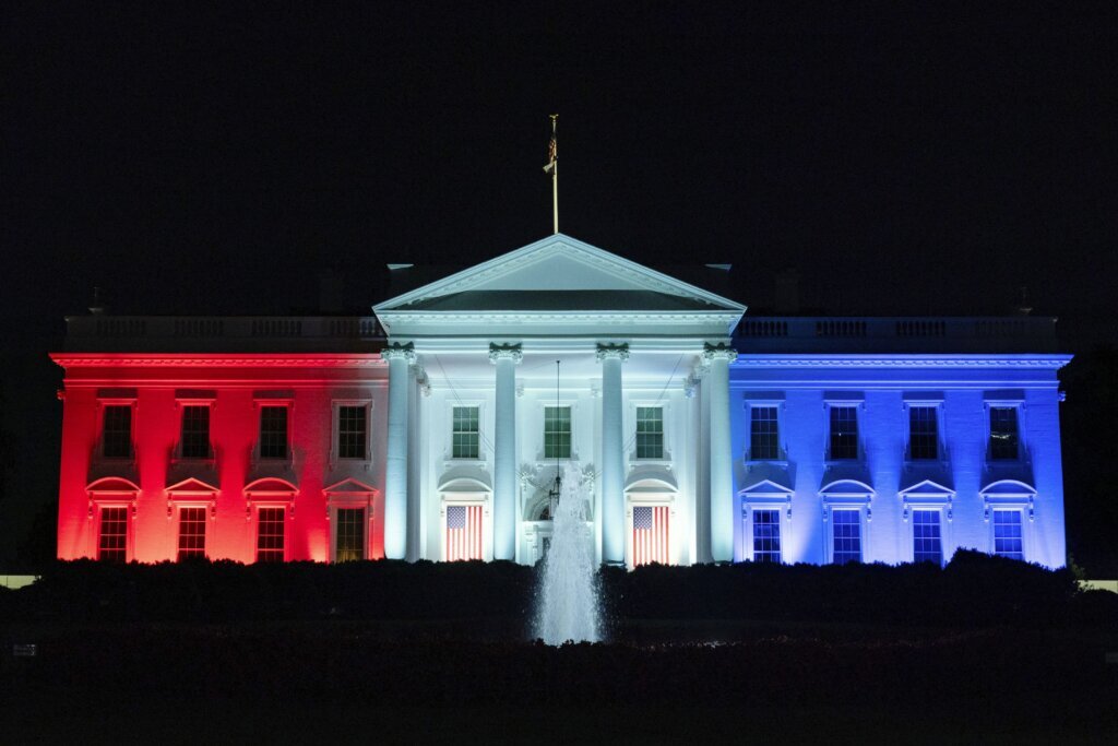 The White House is lit with the colors of the American flag.
