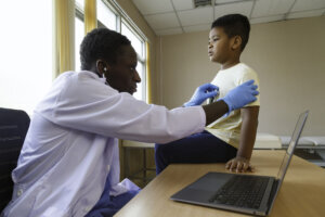 African american man pediatrician doctor using stethoscope to examining little boy from sickness in the office at the hospital. medical and healthy lifestyle concept.