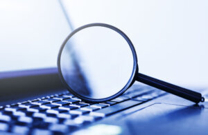 Laptop computer with magnifying glass, concept of search