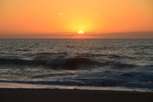 Vibrantly colored sky as the sun peaks up over the Atlantic Ocean on a tranquil morning in Ocean City, Maryland