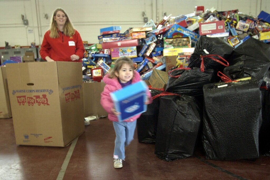 Toys for Tots volunteer behind a girl with toy