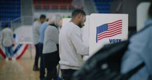 Elderly male voter with bulletin in hands comes to voting booth