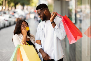 Portrait of happy afro woman showing credit card to man