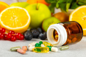 Vitamins and supplements. Variety of vitamin tablets in a jar on a texture background.Multivitamins with fresh and healthy fruits.Food supplements. Flat lay. Space for text.Copy space