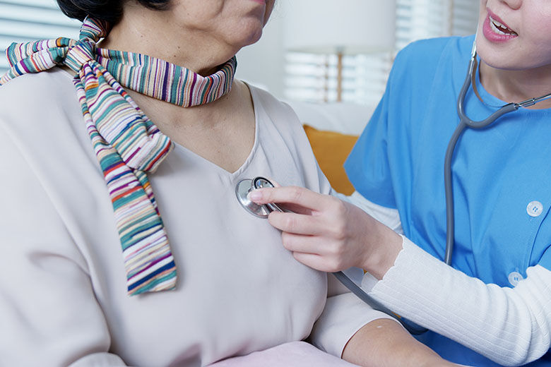 Scrub nurse doctor using stethoscope exam check heartbeat old asia female at home in elderly care cardiovascular medical visit, cardiology cholesterol problem and hospice healthcare caregiver concept.