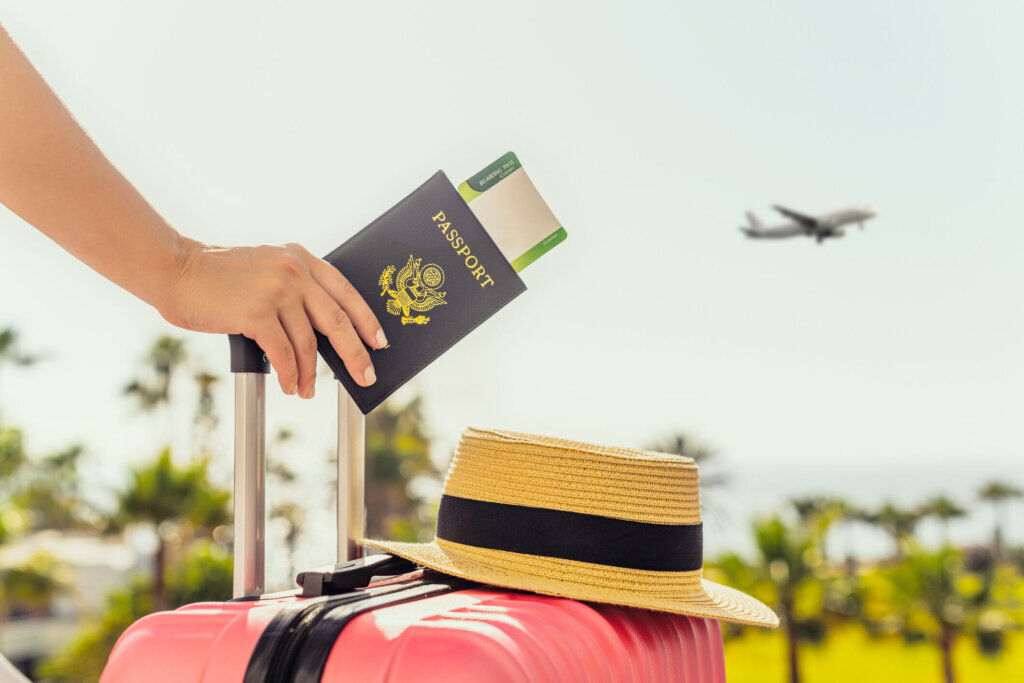 Woman with pink suitcase and American passport with boarding pass.