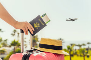 Woman with pink suitcase and American passport with boarding pass.