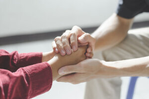 Close up of man psychologist or psychiatrist sitting and holding hands palm of his woman patient for encouragement. PTSD Mental health concept,