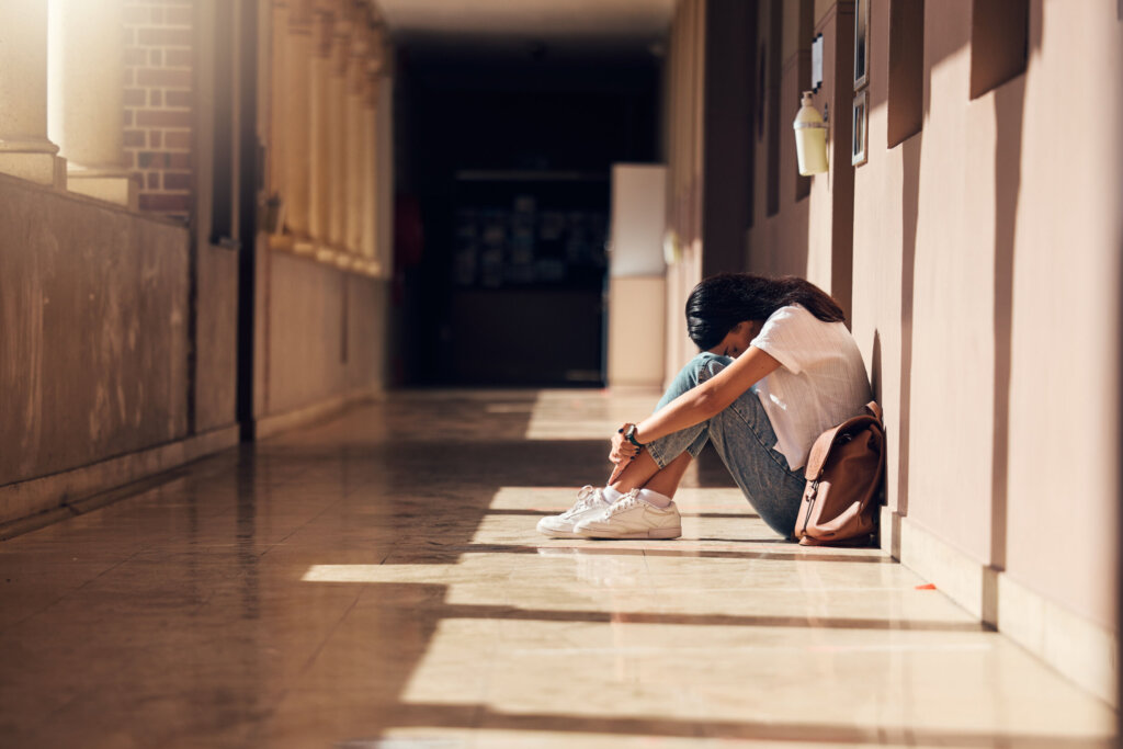 Sad, lonely and girl with depression at school, crying and anxiety after bullying