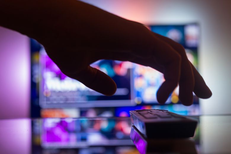 TV with streaming with a remote control near the wall in the room. news and series online. Watching videos on TV. Hand takes TV remote control