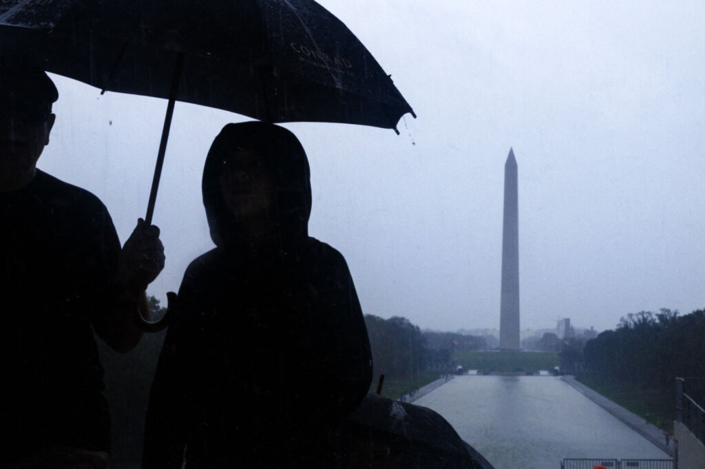 Tourists are seen on the National Mall during heavy rain