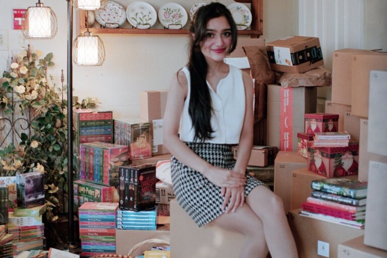 Emily Bhatnagar sits among books for donation