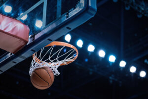 Basketball scoring a basket as it goes through the hoop
