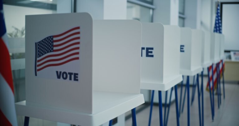 Voting booths with American flag logo in polling station office.