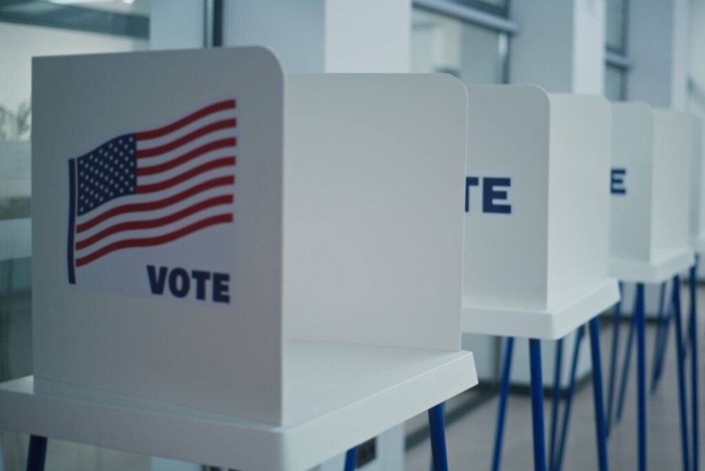 Voting booths with American flag logo in polling station office.