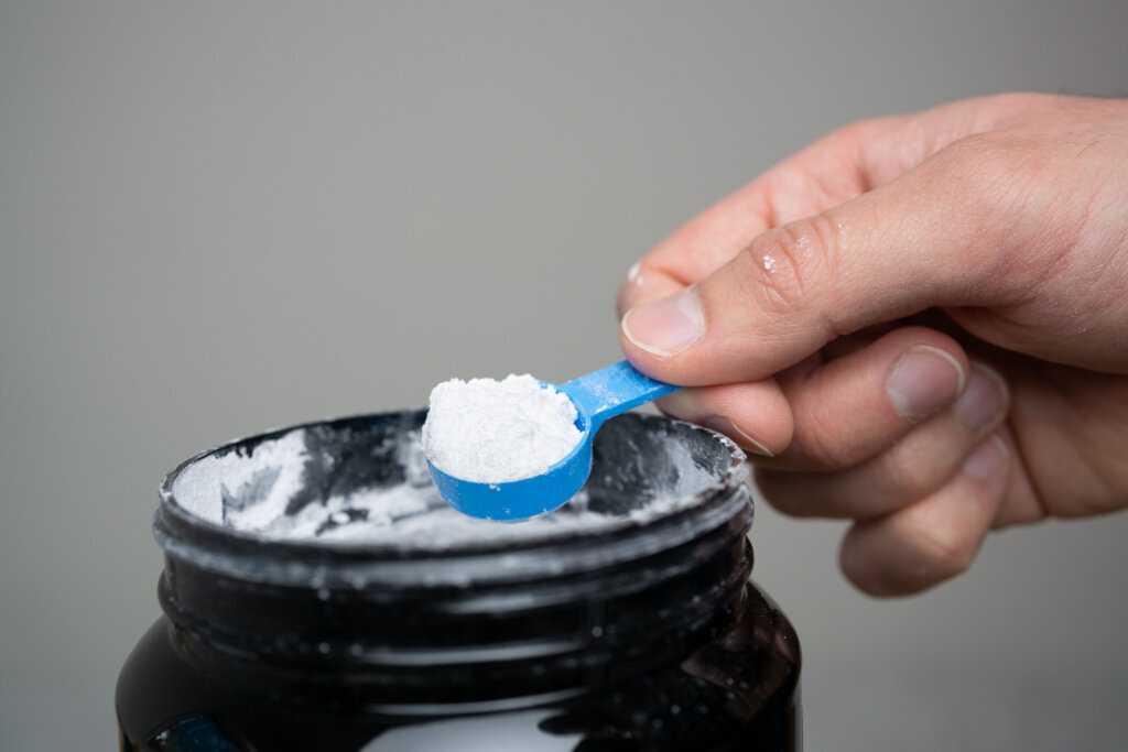 Close up of man hand holding measuring scoop of creatine