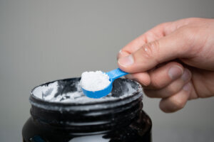 Close up of man hand holding measuring scoop of creatine