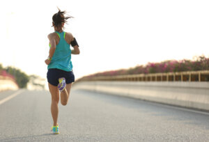 Young woman runner running on city bridge road