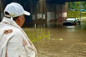 Sandra Byrd looks on at her abandoned Porsche that was flooded on Piney Hill Road in D.C. (WTOP/Jimmy Alexander)