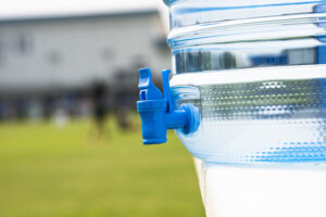 Clear cooler on a white plastic table on a football pitch ready for players in Bangkok, Thailand.