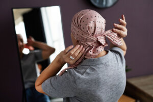 Back view of unrecognizable bald woman tying headscarf