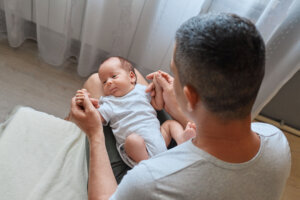 Anonymous father holding his newborn baby in home interior affectionately interacting with his baby gently rocking his newborn
